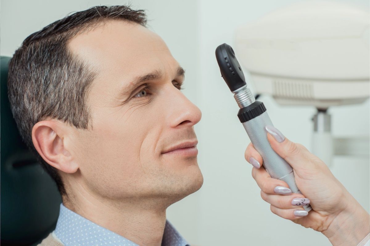 Man's eye being examined with an ophthalmoscope in an eye doctor's office.