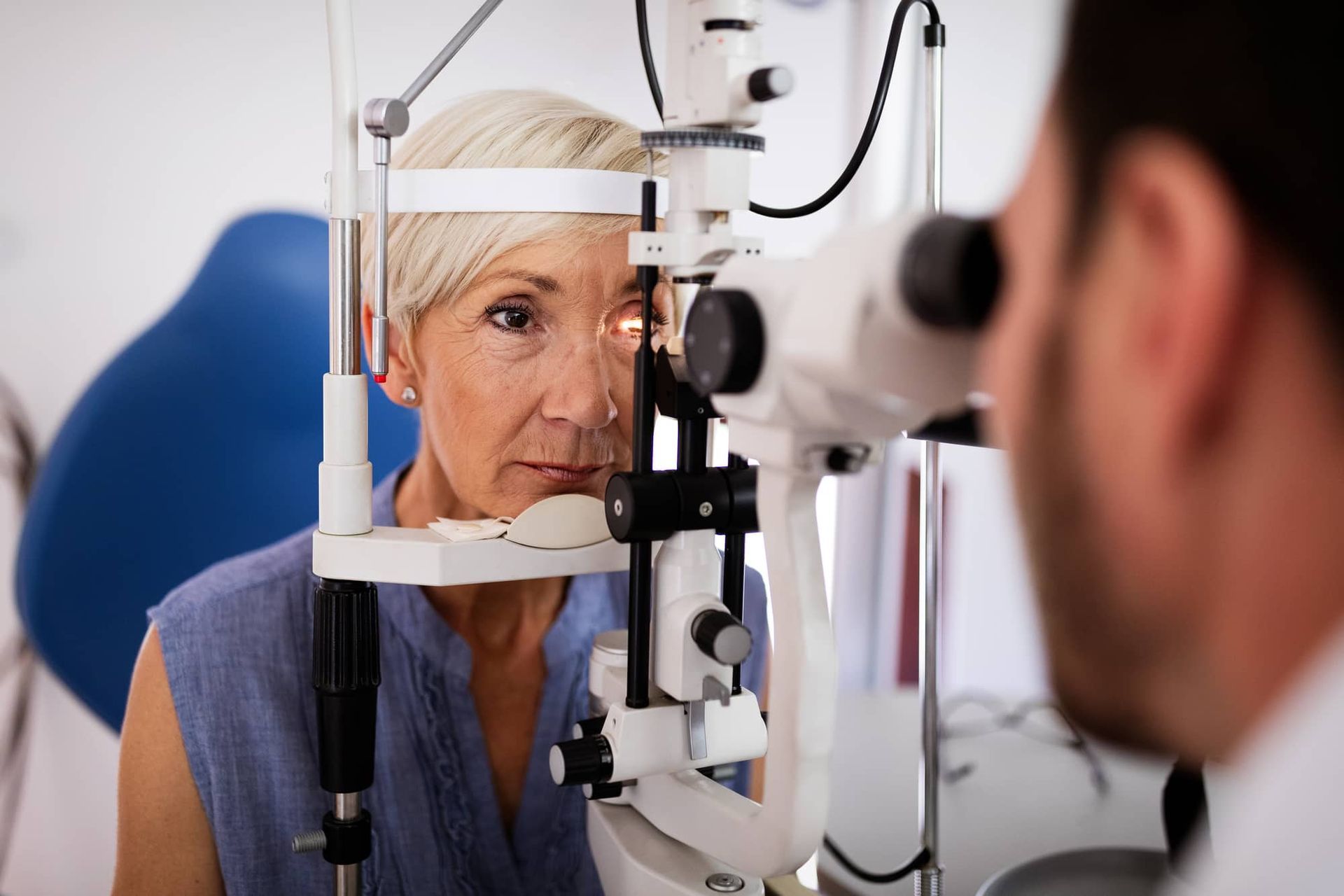 Middle-aged woman getting eye exam with a slit lamp, doctor looking in her eye.