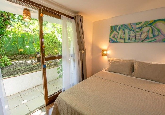 Quarto com cama, porta de vidro deslizante para um pátio e obras de arte na parede.