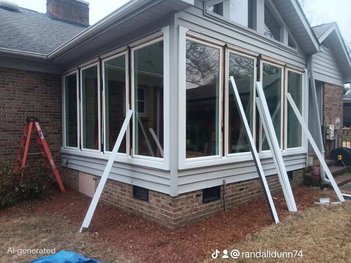 Sunroom with large windows, exterior view. White supports prop up the windows, red ladder nearby.