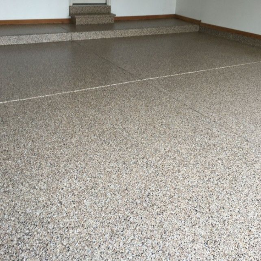 Garage with flake speckled floor with a step and baseboard in a plain indoor room