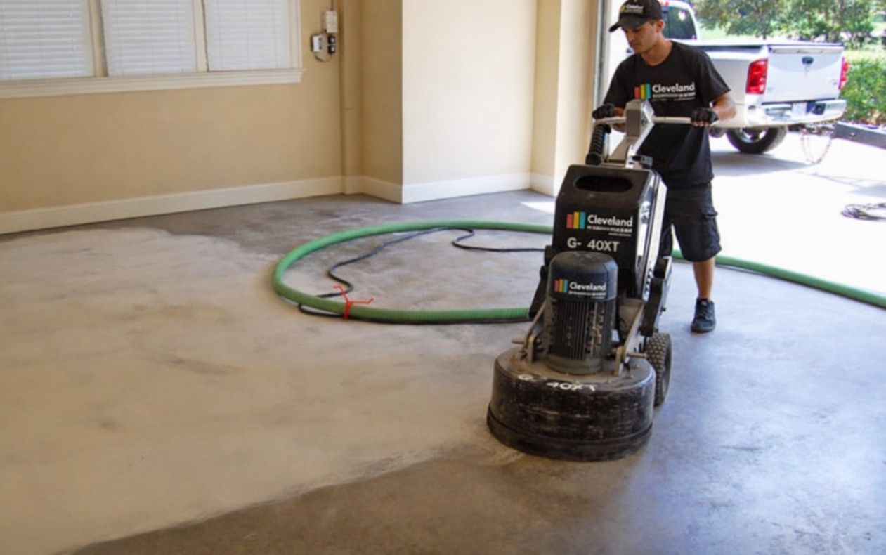 Cleveland Epoxy & Coating Pros contractor using a floor buffer on a bare concrete floor inside a garage to prep for epoxy install.