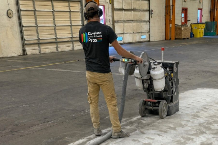 Cleveland Epoxy & Coating Pros worker operating a floor grinder in a commercial garage, grinding and smoothing a concrete floor.