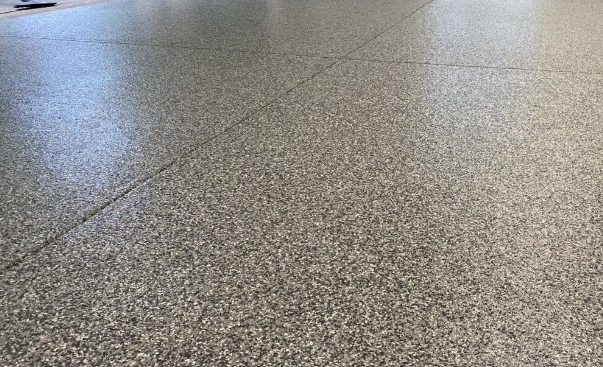 Clean flake-coated garage floor with a smooth finished surface and organized layout, showing how flake flooring creates a space that looks easier to maintain and keep clean day to day.