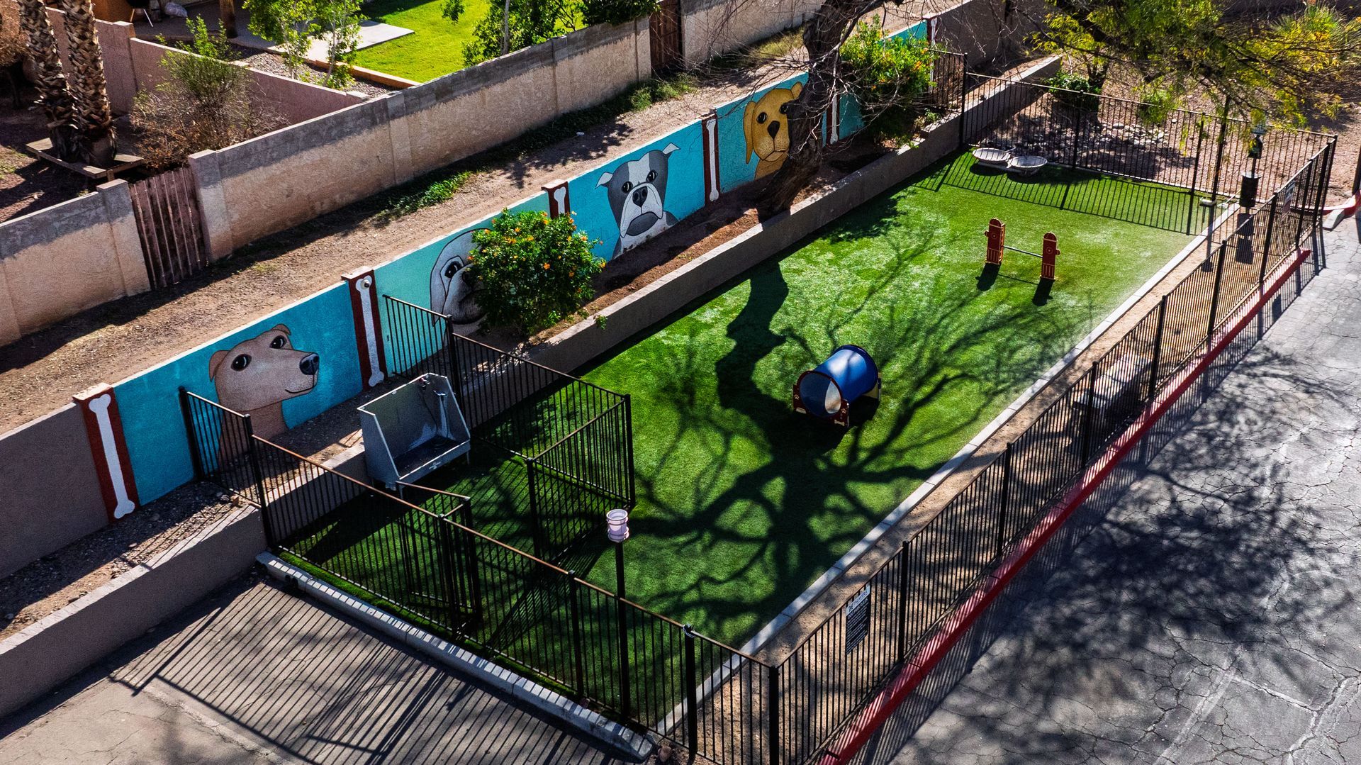 Apartment complex with a pool, red tile roofs, white buildings, and palm trees under a bright blue sky. Discover flexible living in 2 bedroom apartments in Tempe AZ at Talavera Apartments.