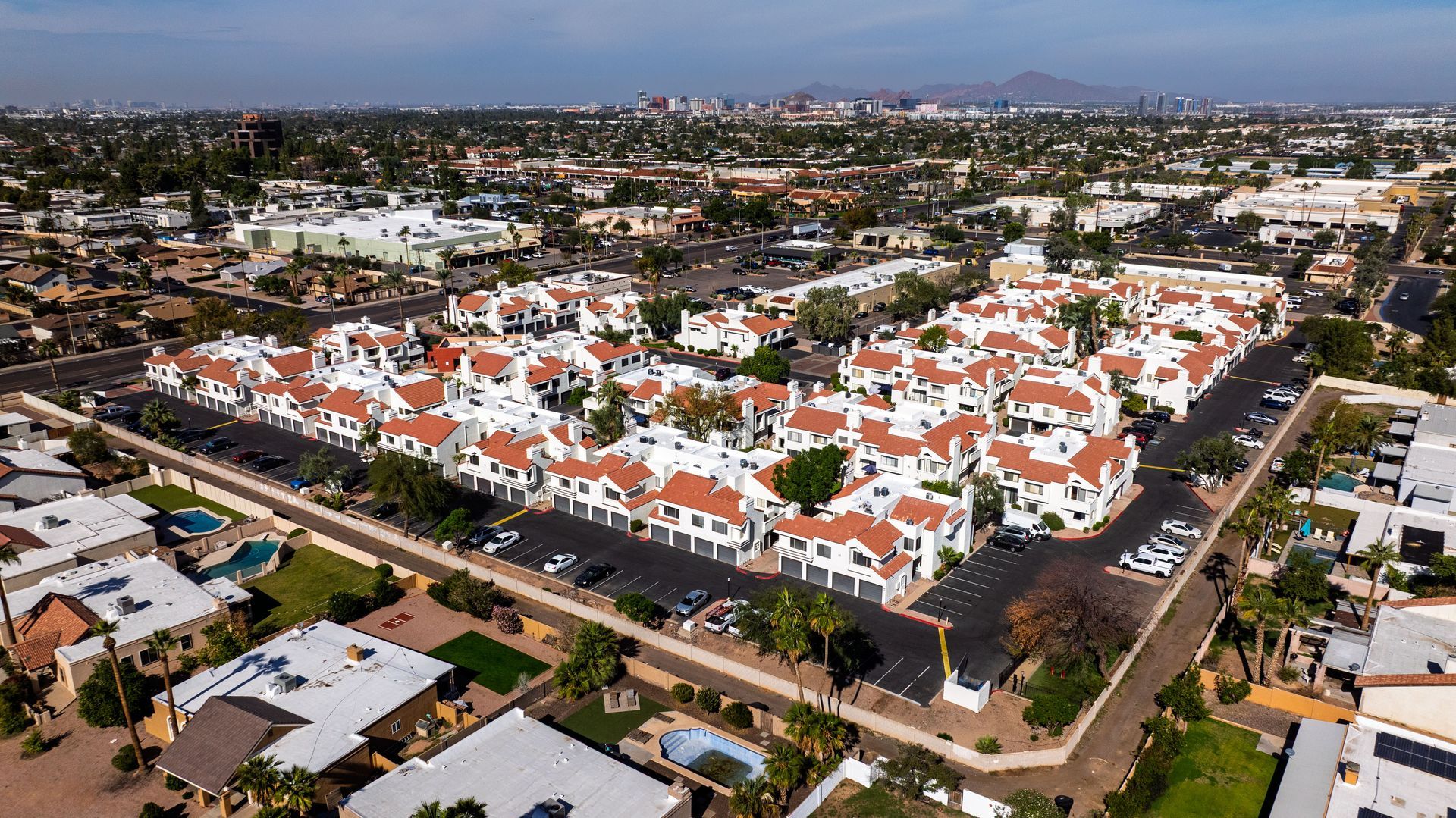 Aerial view of white buildings with red roofs in a city neighborhood, surrounded by roads and greenery. Talavera Apartments offers thoughtfully designed apartment homes in Tempe AZ—explore more.