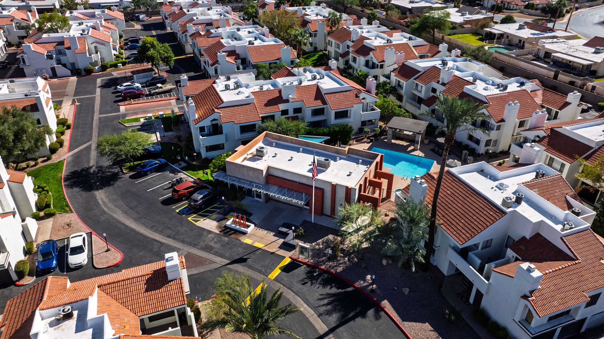 Aerial view of residential buildings with red tile roofs and a pool. Talavera Apartments features inviting pet-friendly apartments in Tempe AZ today.