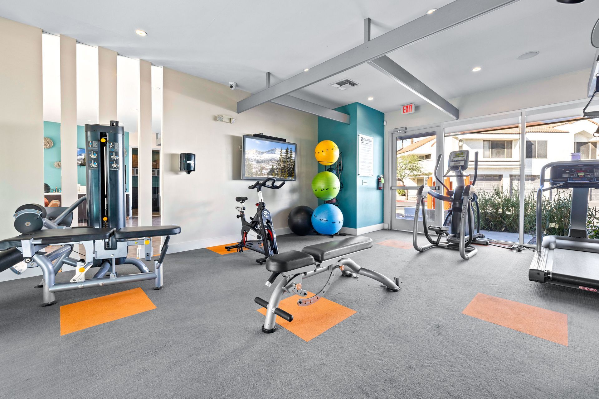 Gym interior with exercise equipment: weight machines, treadmills, exercise balls, and a TV. Discover spacious 2 bedroom apartments in Tempe AZ at Talavera Apartments today.