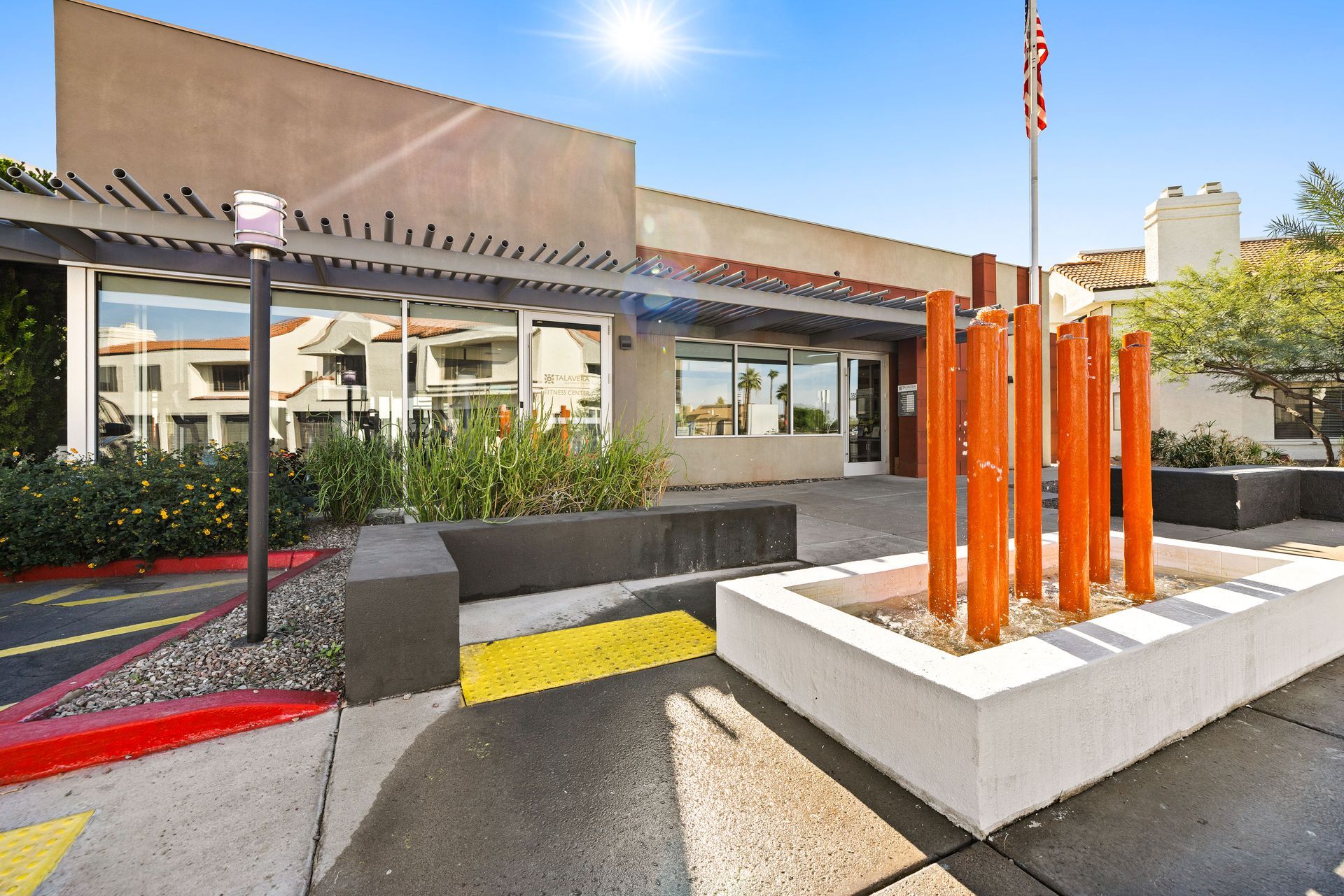 Building exterior with orange art sculpture, flag, and reflective windows. Talavera Apartments delivers contemporary apartments in Tempe AZ—take a look.