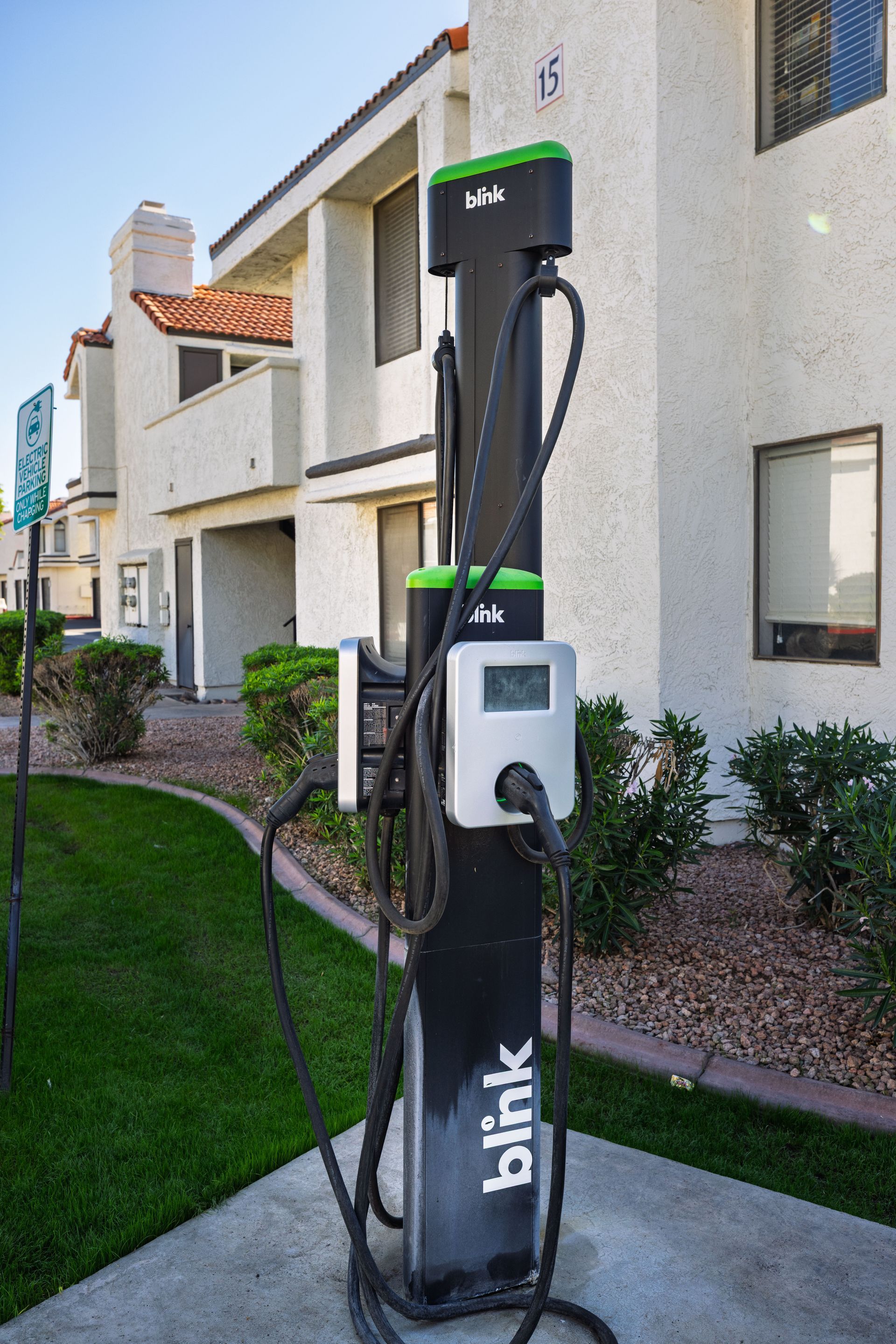 Blink electric vehicle charging station in front of a beige apartment building with green trim. Enjoy everyday living in a pet-friendly community at Talavera Apartments.