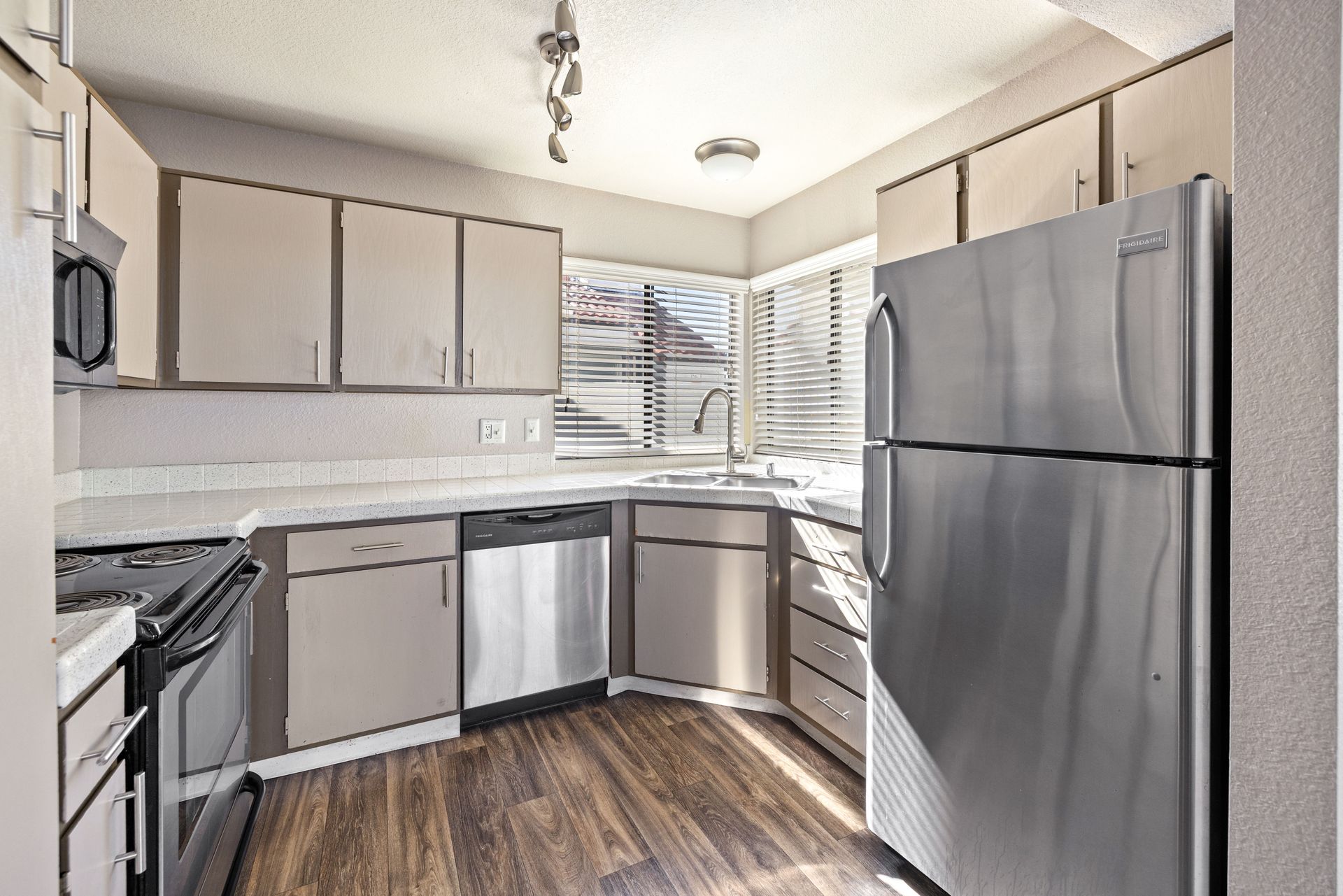 Kitchen with stainless steel appliances, light cabinets, and dark wood-look flooring. Experience downtown Tempe apartments at Talavera Apartments—take a closer look.