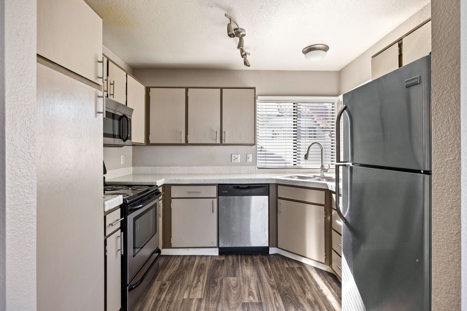 Kitchen with cabinets, stainless steel appliances, and wood-look flooring.