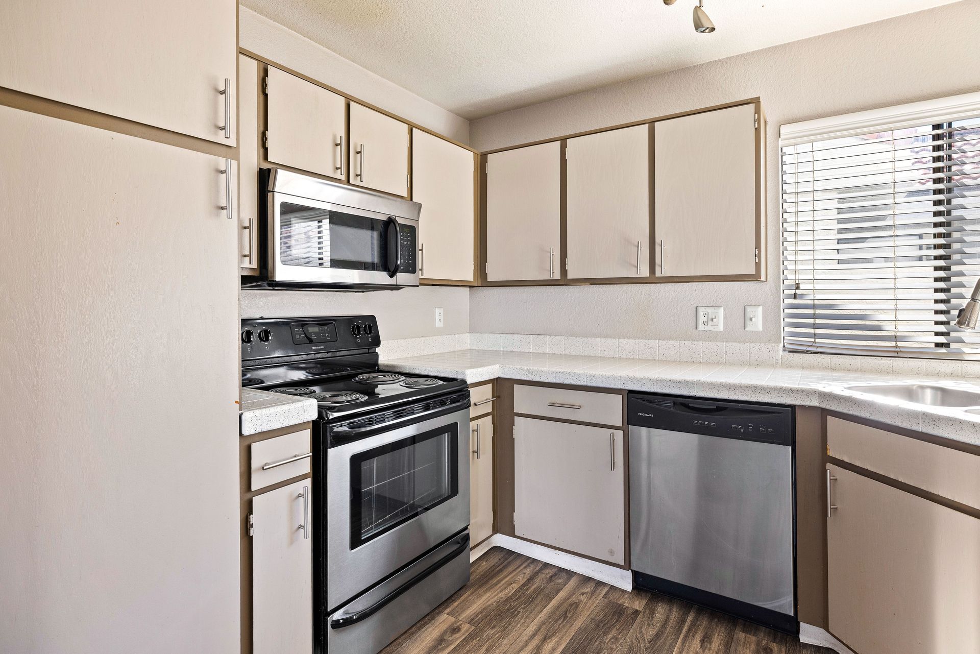 Kitchen with stainless steel appliances, light cabinets, and a window with blinds. Talavera Apartments offers modern apartments in Tempe AZ—explore your next home today.