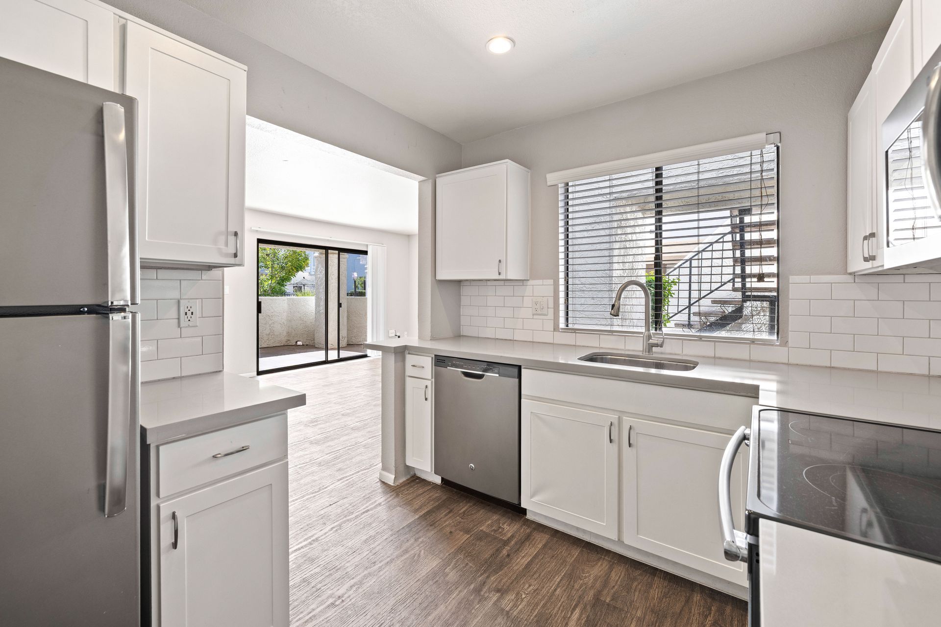 Modern white kitchen with stainless steel appliances, window, and view of a patio. Talavera Apartments is a welcoming pet-friendly community—come see it for yourself.