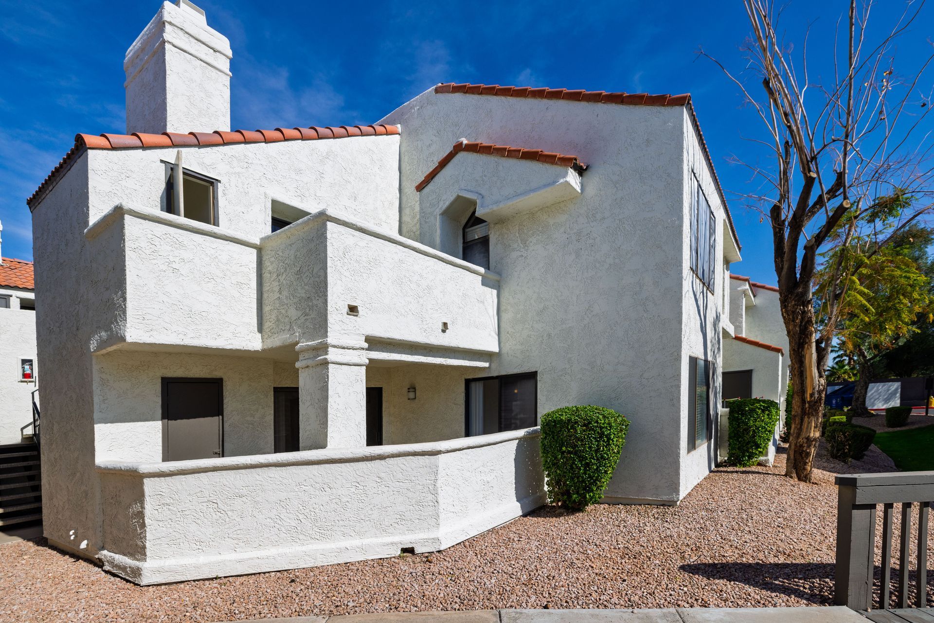 White stucco apartment building with red tile roof and balconies on a sunny day. Explore cozy 1 bedroom apartments in Tempe AZ at Talavera Apartments.