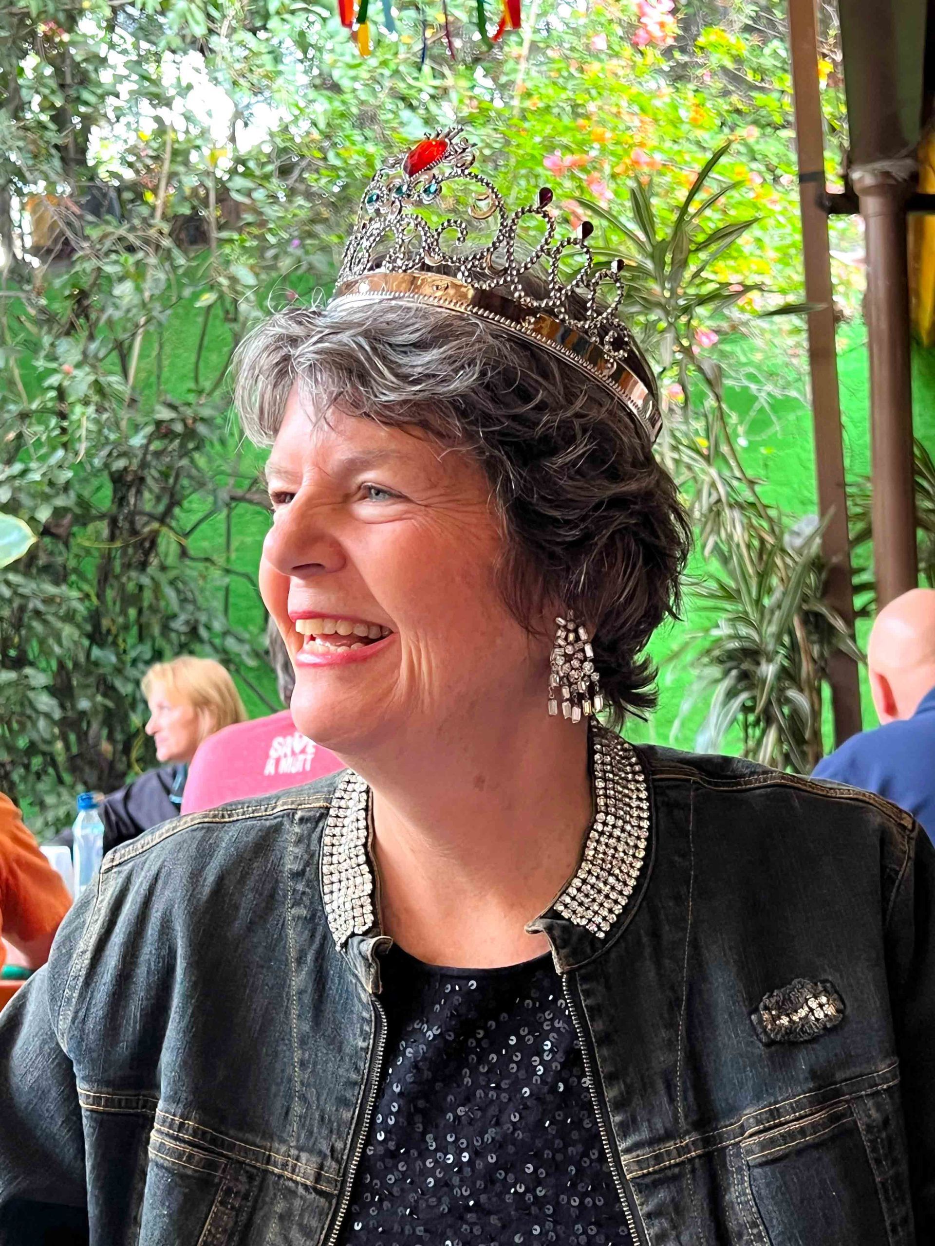 Woman on a TEDx stage, wearing blue and black, speaking. Stage backdrop with the word