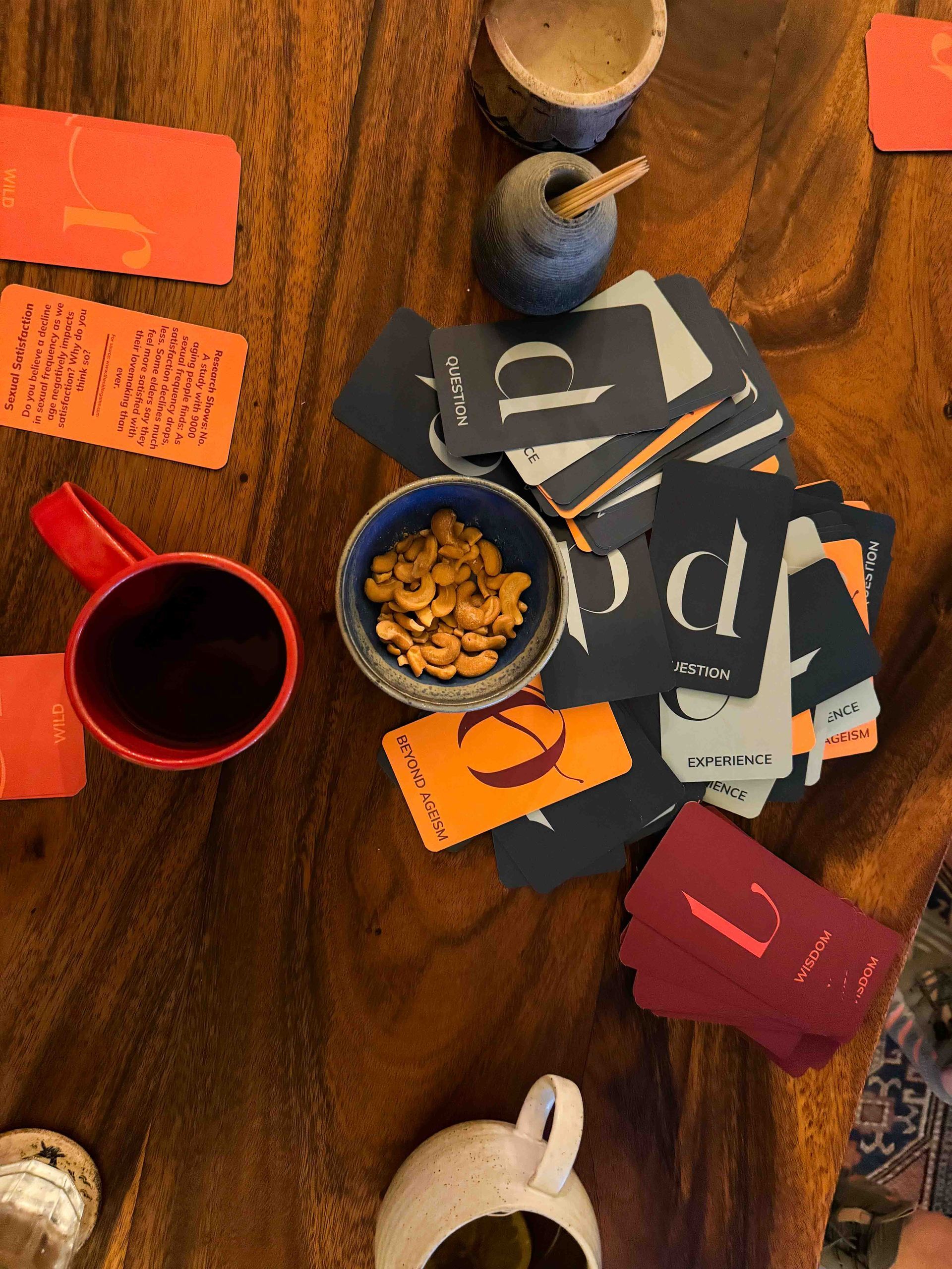 Wooden table with snacks, cups, cards, and small bowls.