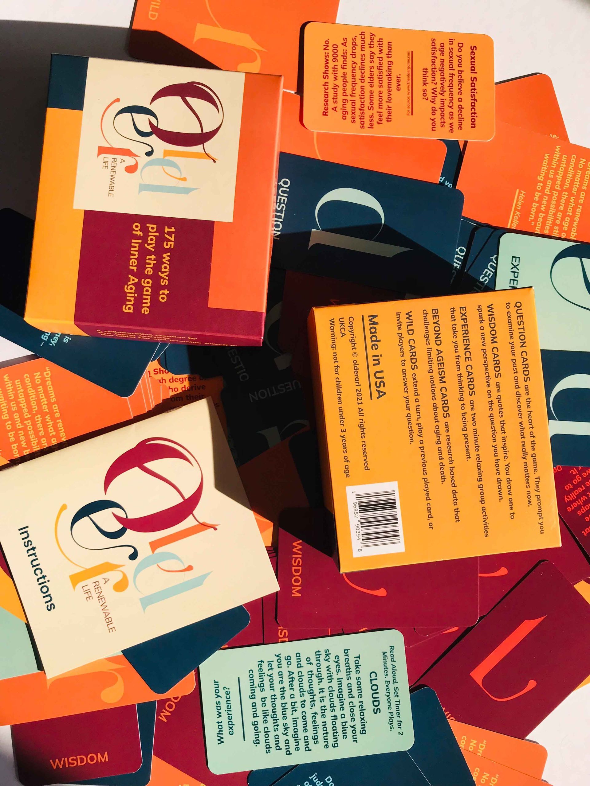 Books and cards scattered; colorful text and design. Boxes: orange, burgundy. Cards: turquoise, orange, burgundy.