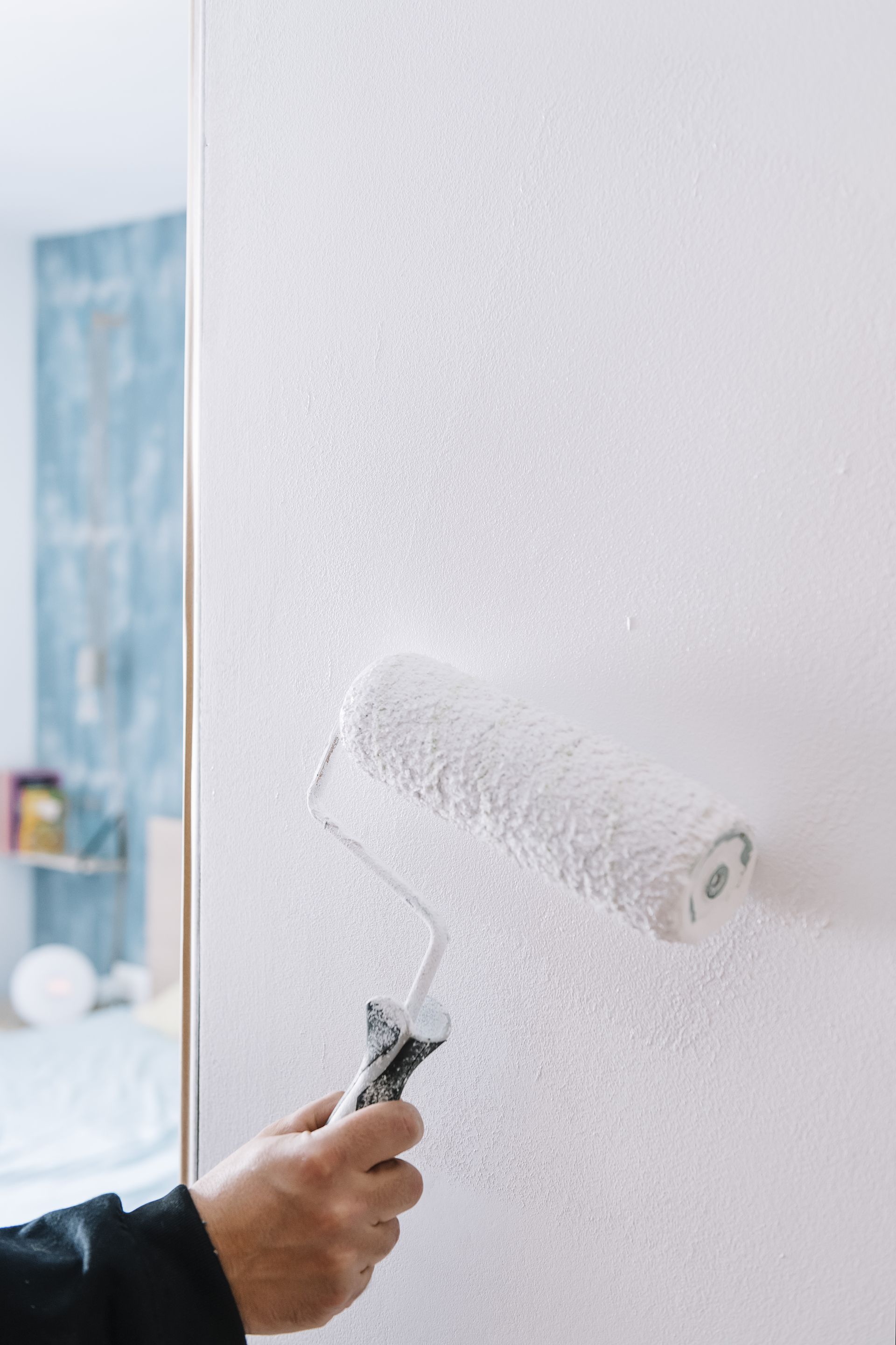 Hand painting white paint on a wall with a roller. Hand painting white paint on a wall with a roller.