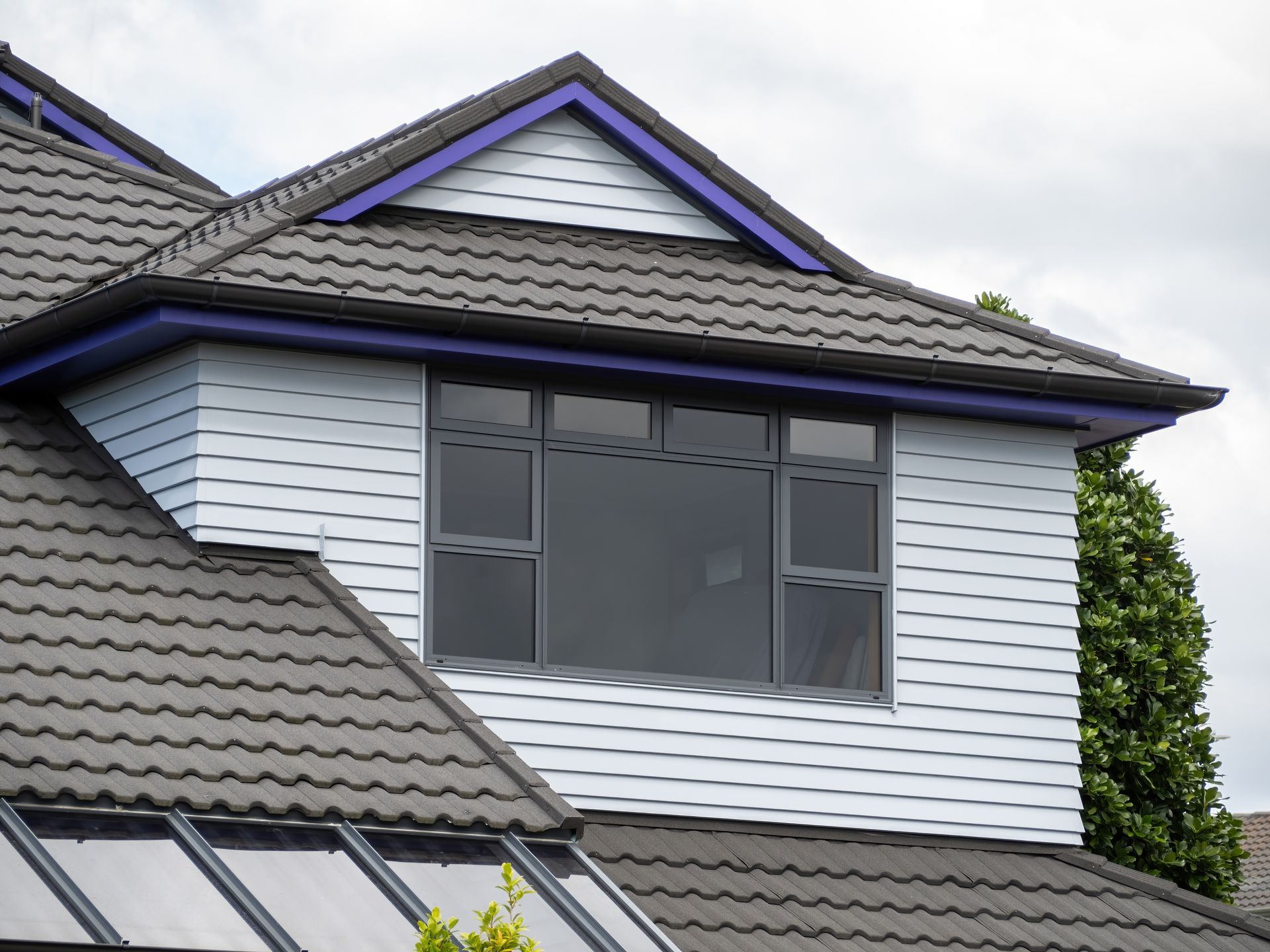 Wooden house with gray metal roof, chimney, and windows against a clear blue sky. Wooden house with gray metal roof, chimney, and windows against a clear blue sky.
