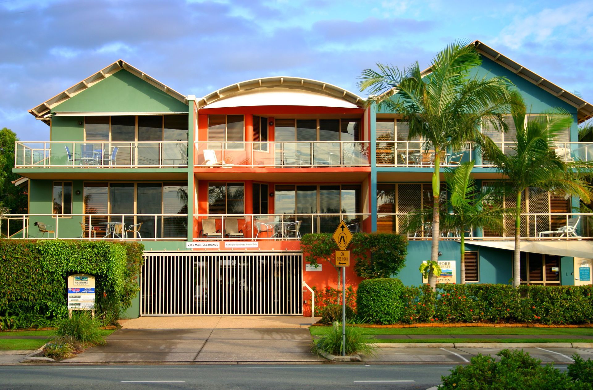 Colorful multi-story apartments with balconies and palm trees.