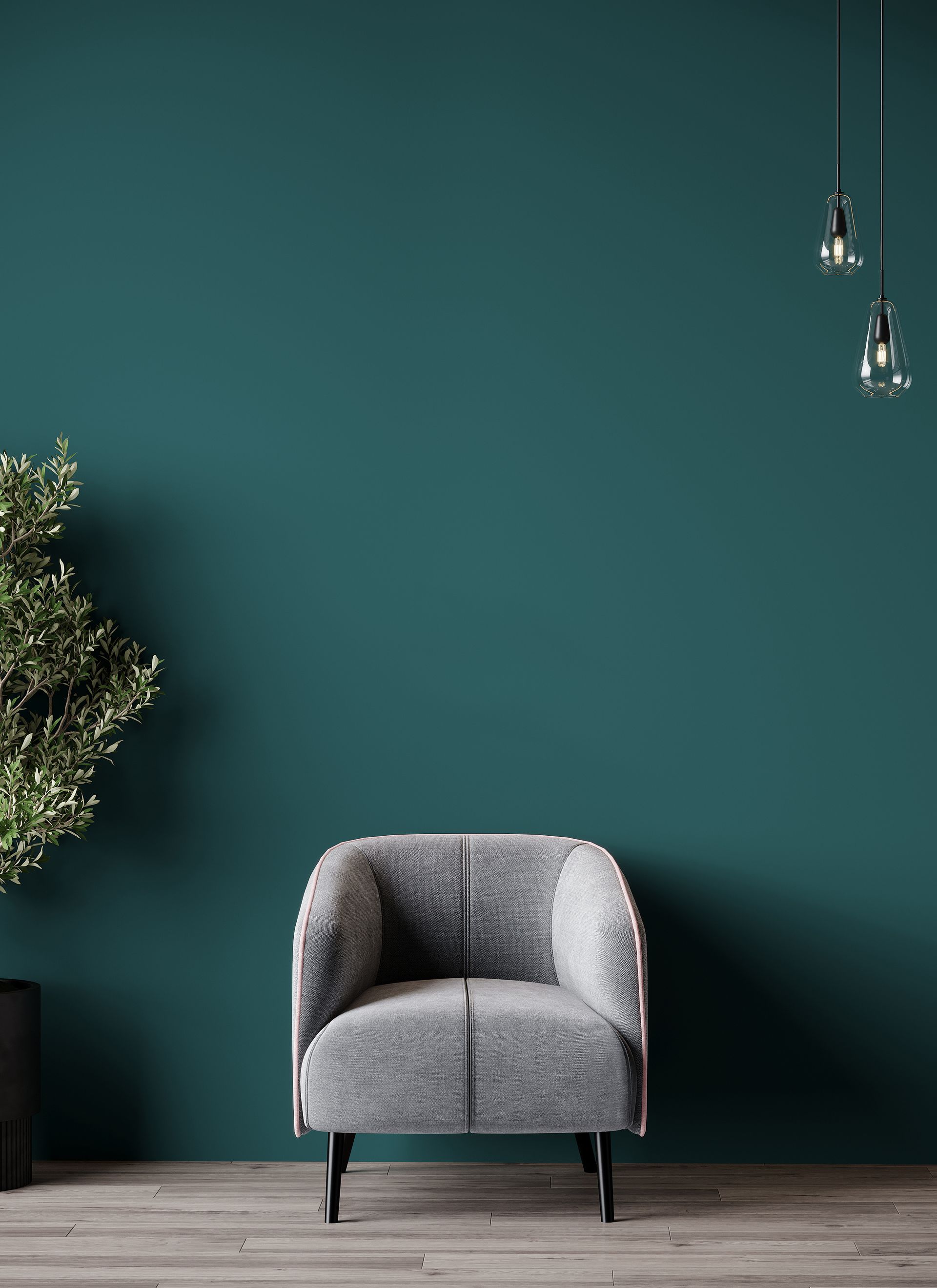 Gray armchair in front of a teal wall, with a plant and hanging light fixtures.