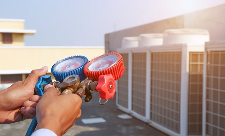 Une personne tient deux jauges dans ses mains devant un bâtiment.