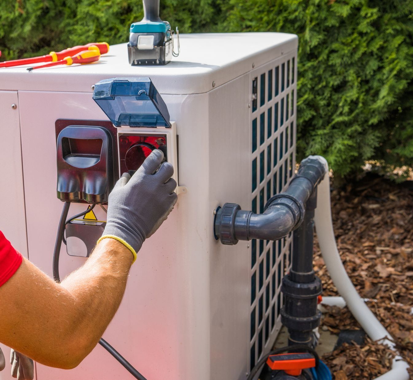 Un homme portant des gants travaille sur un climatiseur à l'extérieur.