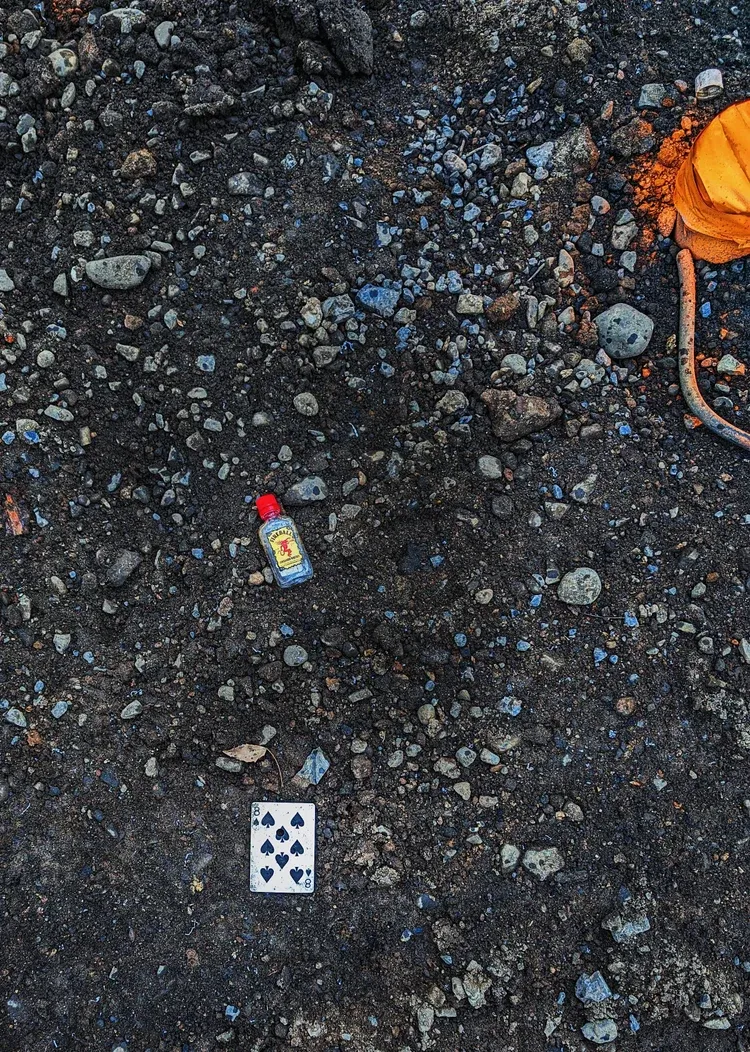 Dark ground with small rocks, a bottle, and a white and black scale. Orange marking on the top right.