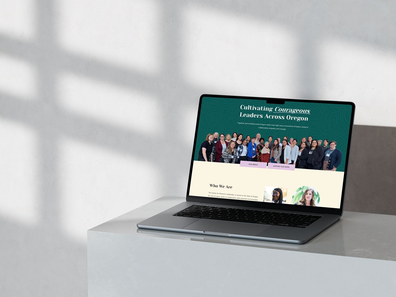 Laptop displaying a webpage with a group photo on a white surface with shadows.