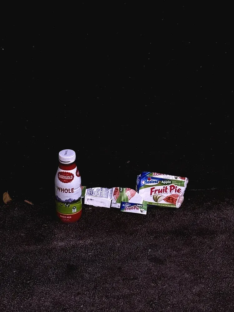 A bottle of Del Monte juice, two juice boxes, and a fruit pie box on a dark, rough surface.