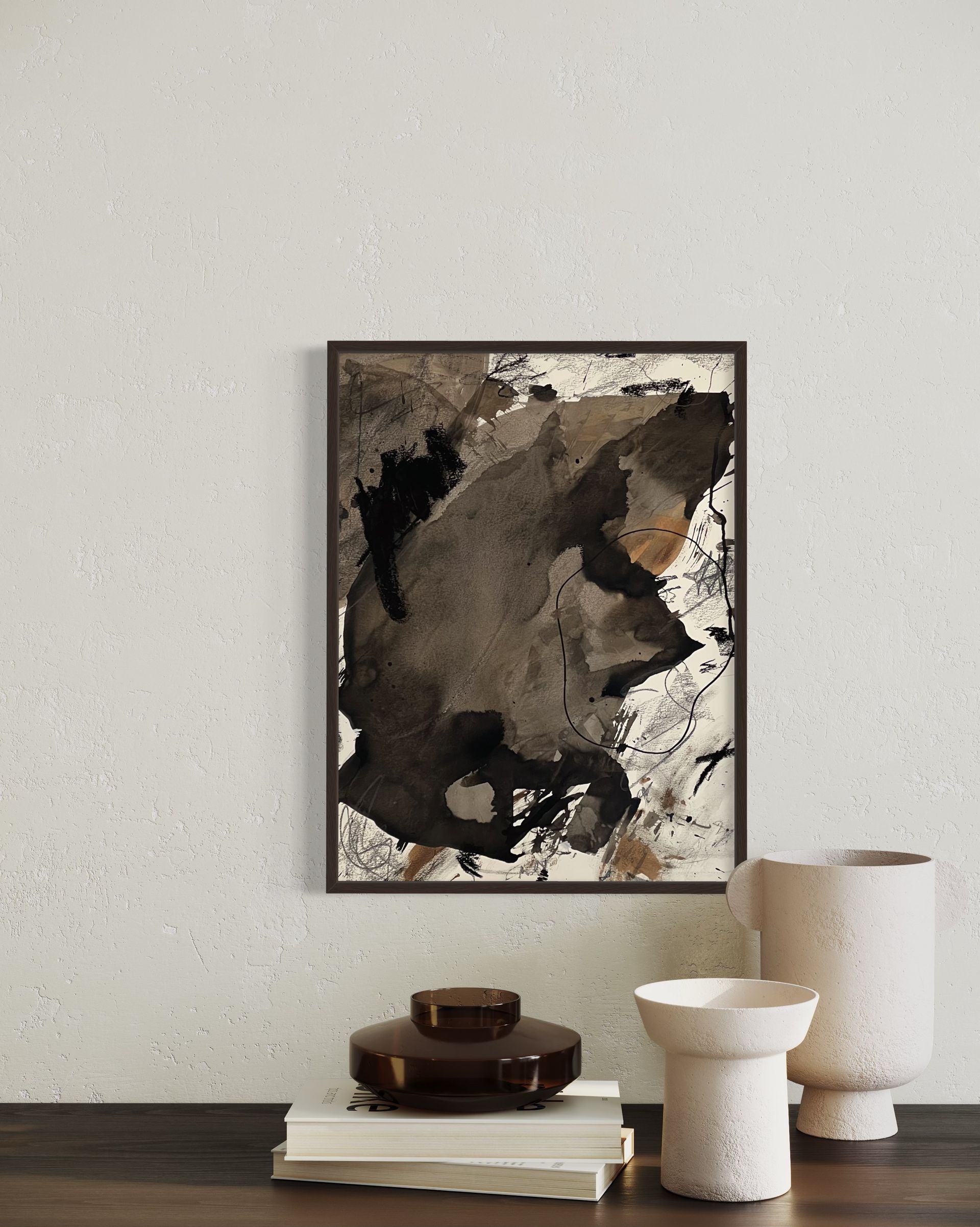 Abstract art in a dark frame hangs above vases on a wooden surface against a textured wall.