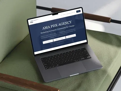 Laptop displaying a website for AMA PDX agency, resting on a green chair.