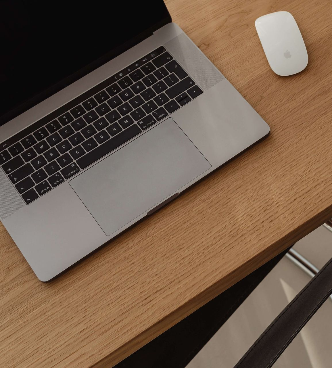 Laptop and white mouse on a light wood desk.