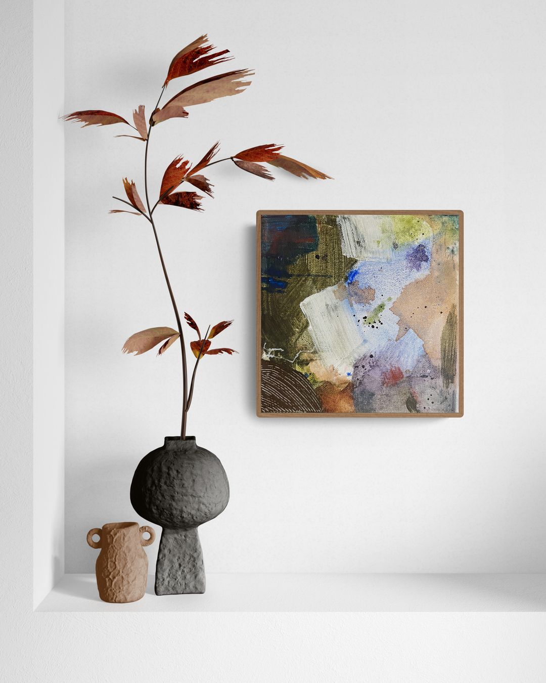 Abstract painting and dried plant in a vase on a white shelf. Earth tones, brown frame.