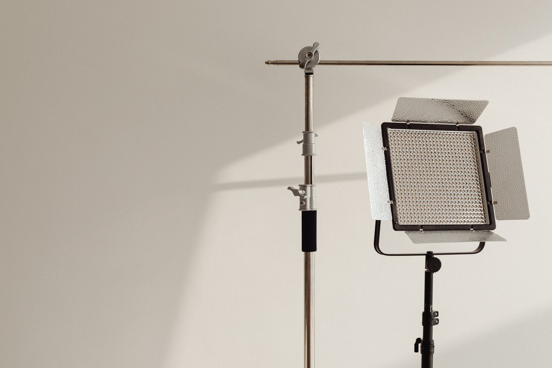 Studio lighting equipment: LED panel on a stand, casting light on a white background.