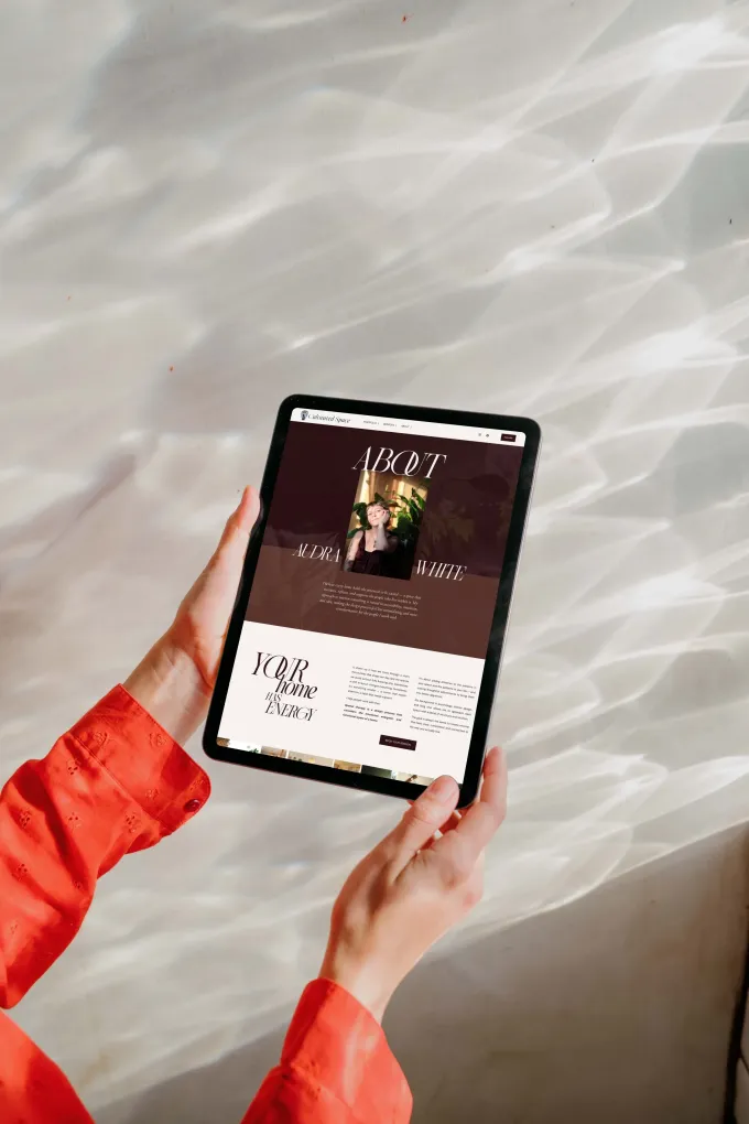 Hands holding tablet with website on screen. Brown and white theme.