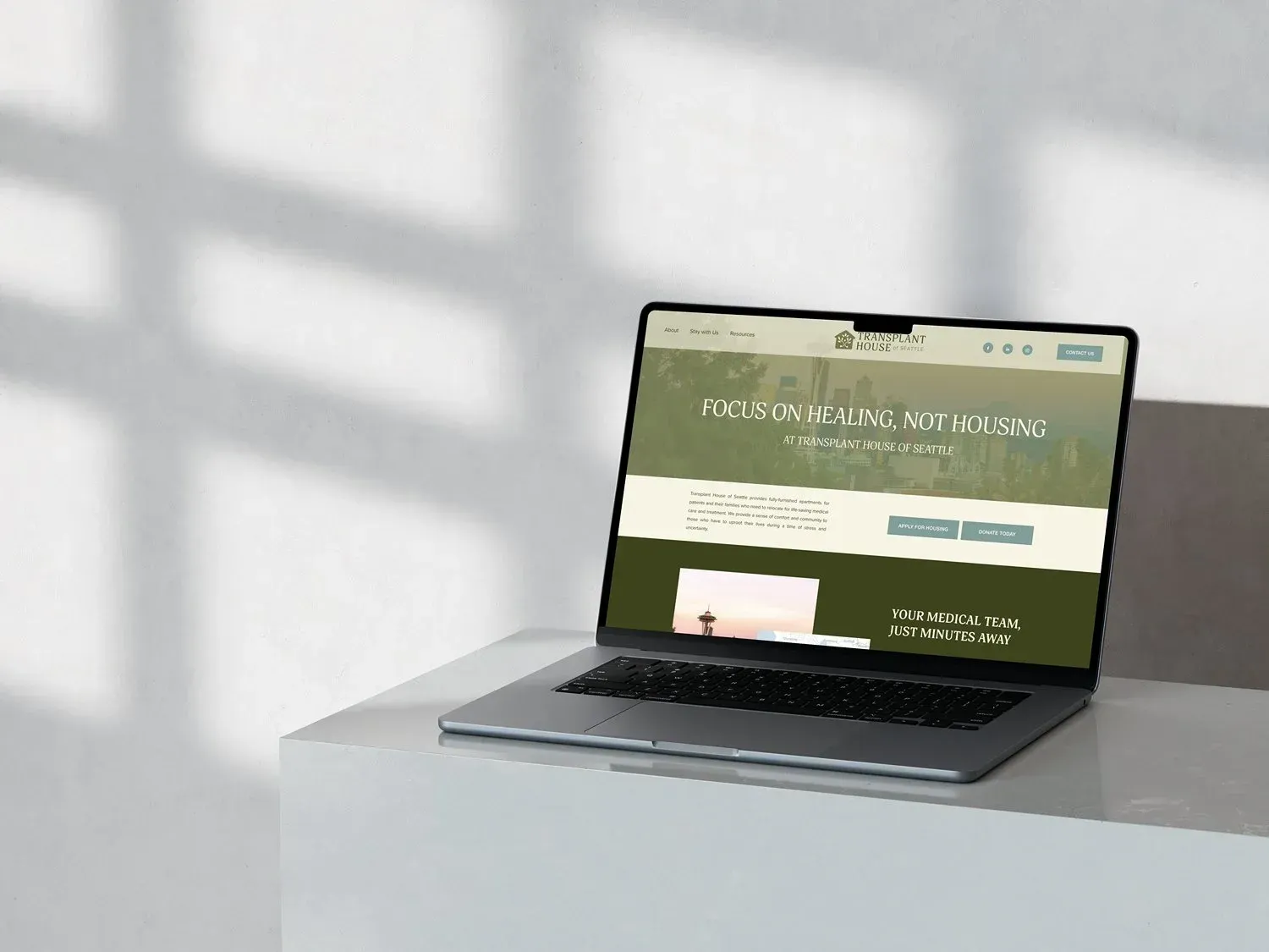 Laptop displaying a website on a white surface with shadows.