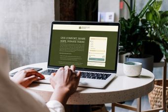 Person using a laptop on a table with a booking form displayed on the screen.