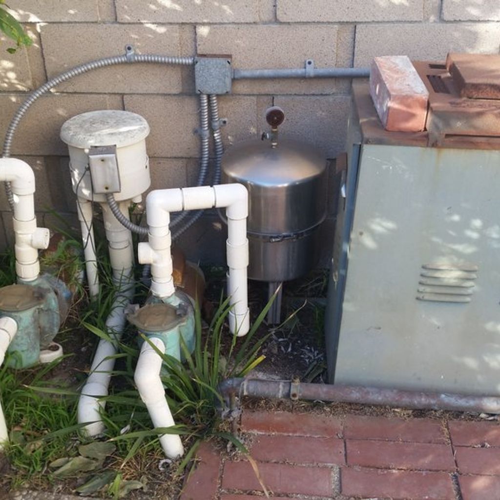 A stainless steel tank is sitting next to a brick wall