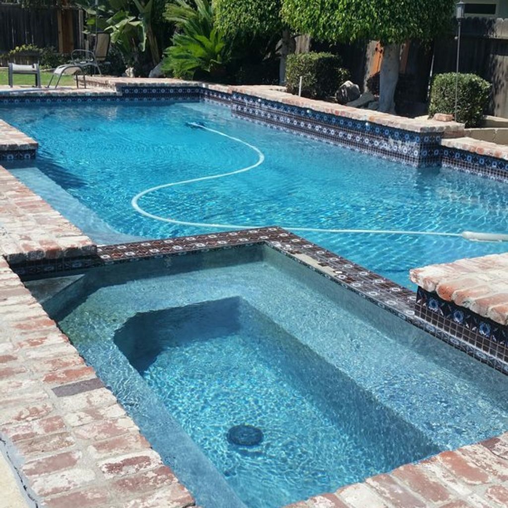 A large swimming pool with a hot tub in the middle.