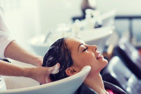 Un parrucchiere lava i capelli di una cliente