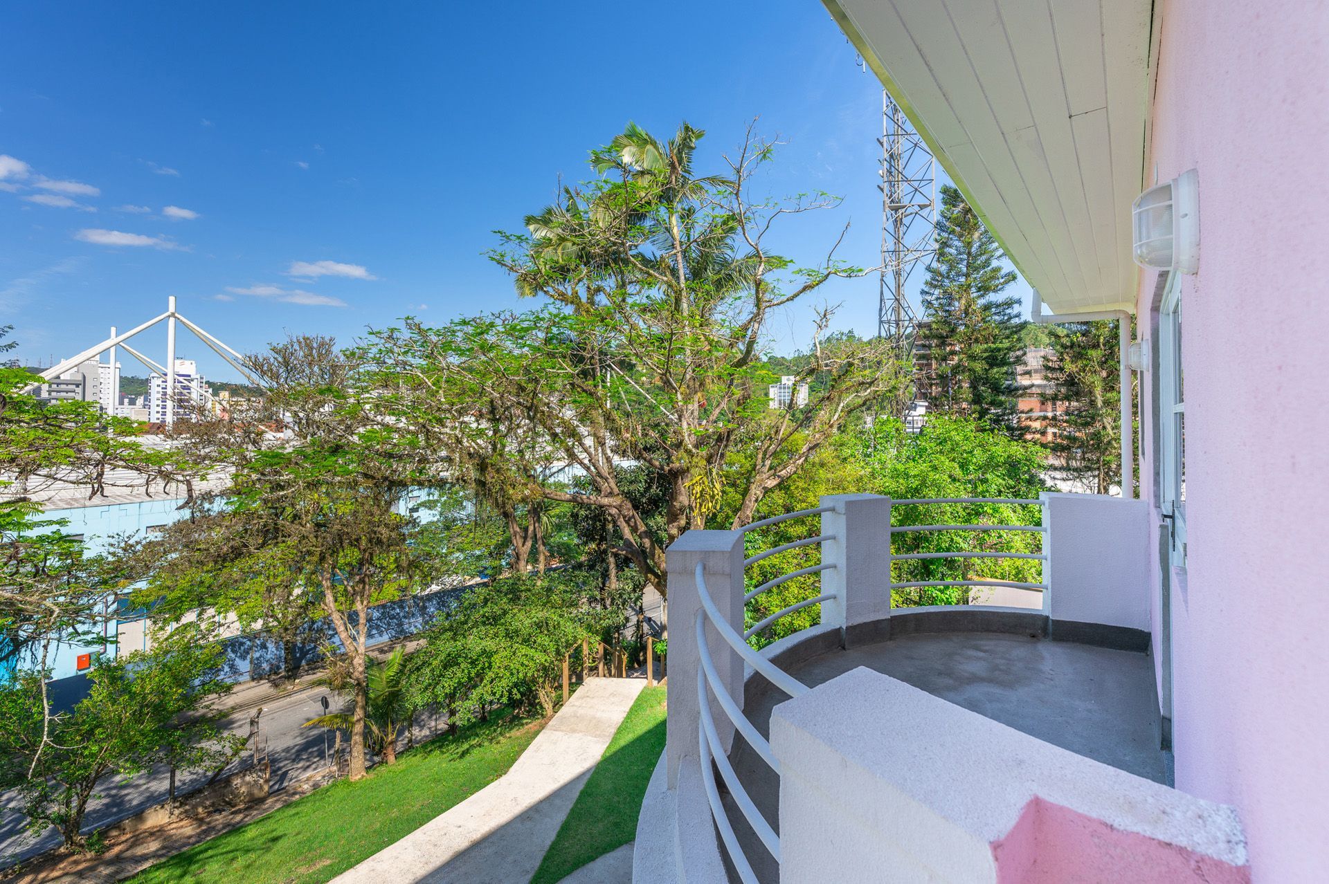 Vista da varanda para árvores verdes, um parque aquático e um céu azul em um dia ensolarado.