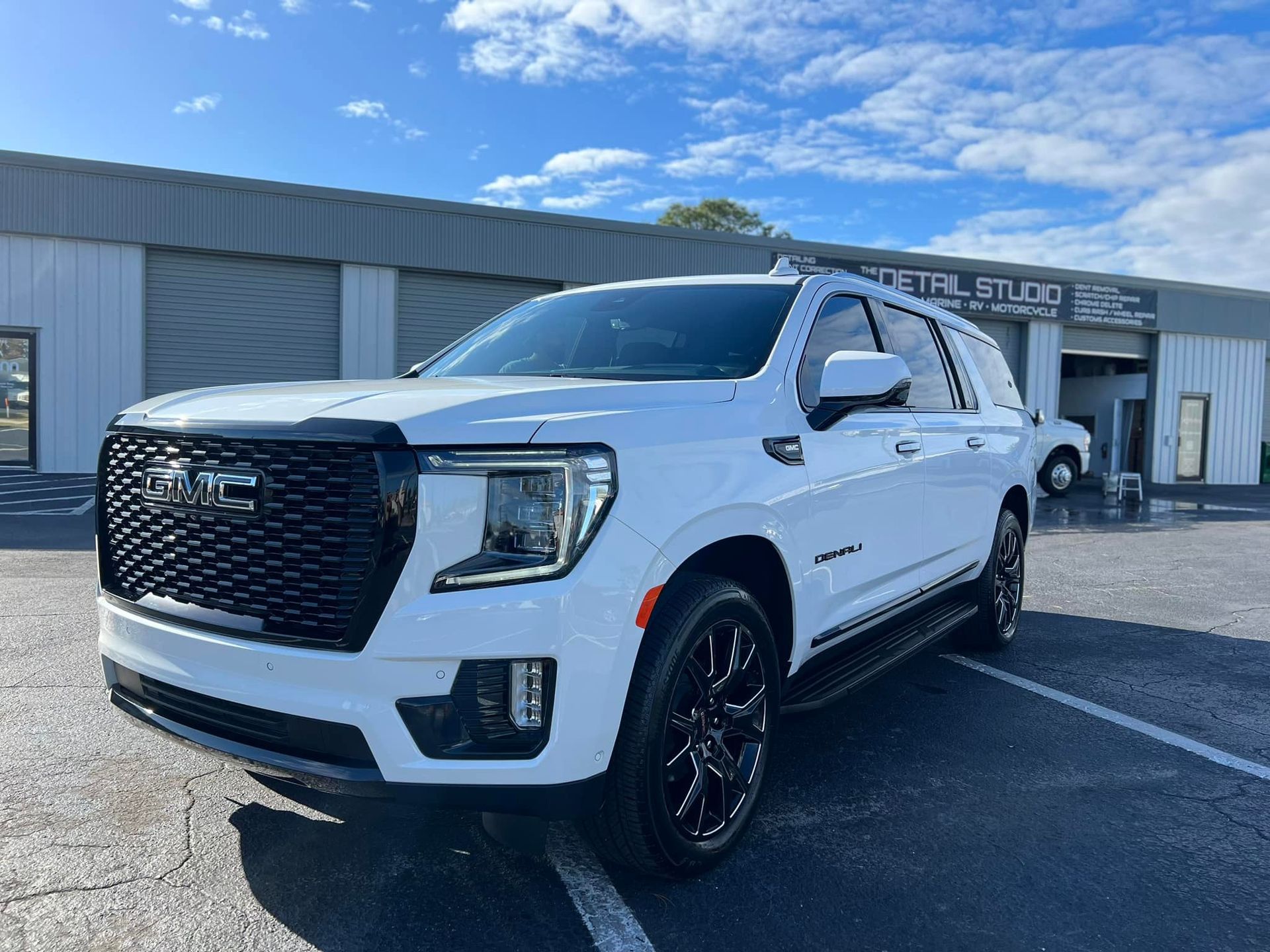 A white gmc yukon is parked in a parking lot in front of a building.