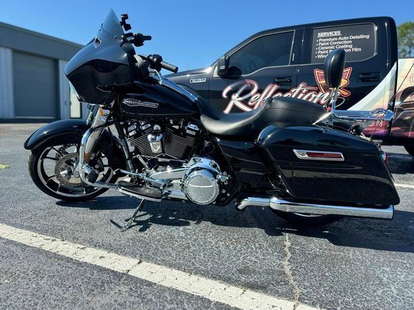 A black harley davidson motorcycle is parked next to a reflection van