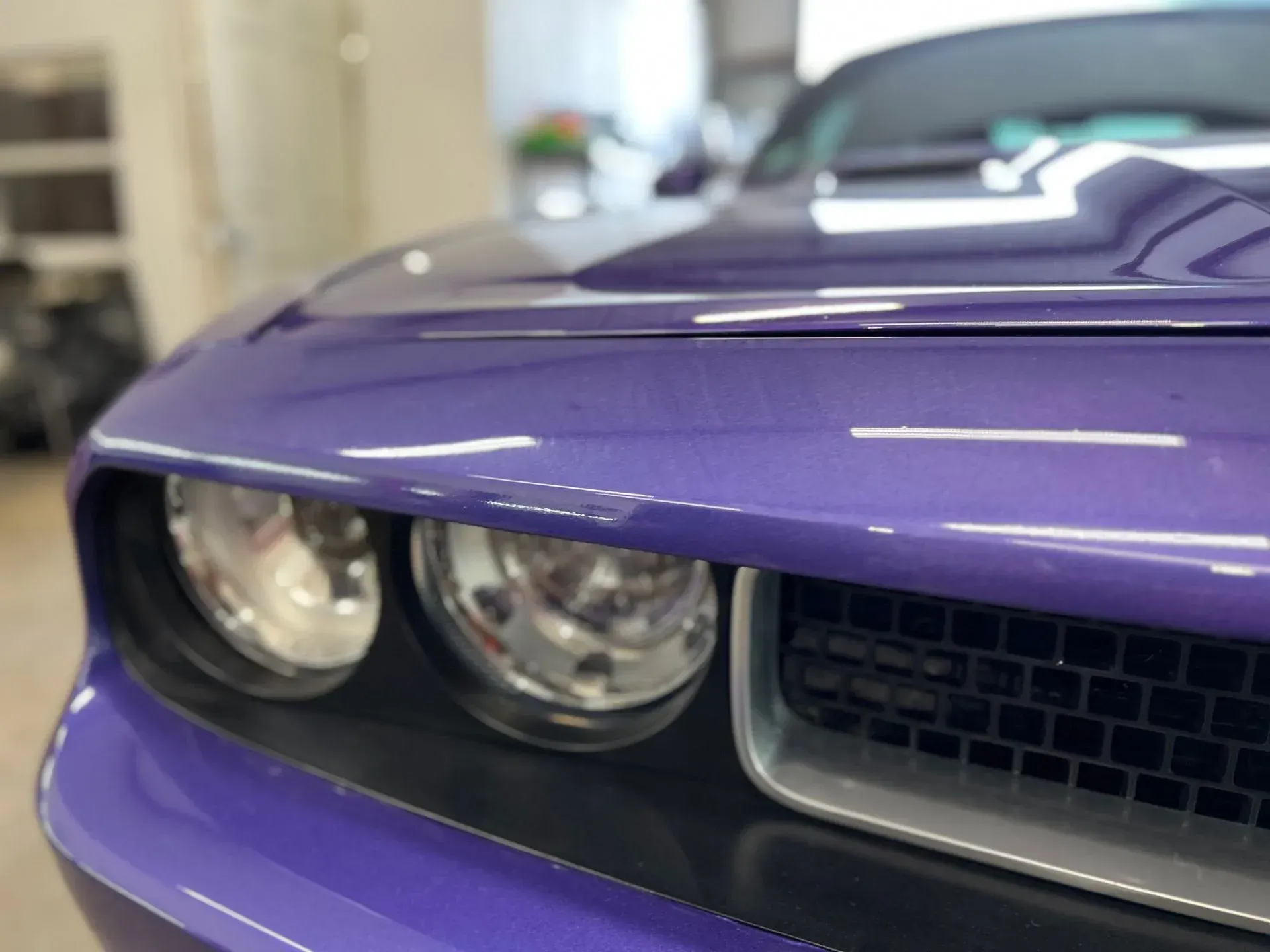 A purple dodge challenger is parked in a garage