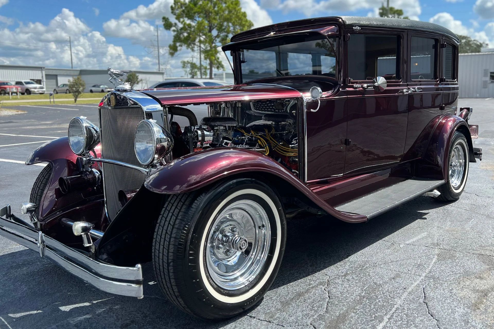 A burgundy vintage car is parked in a parking lot.