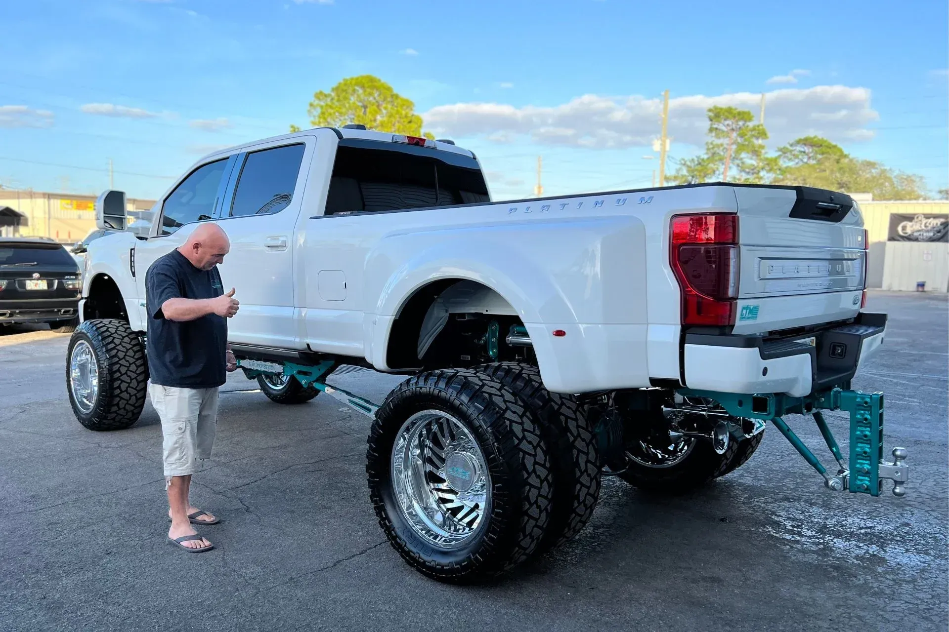A man is standing next to a white truck in a parking lot.