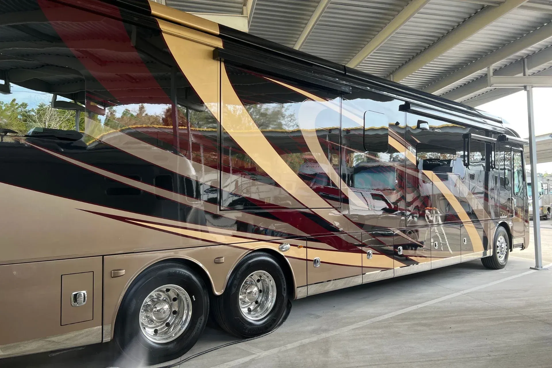 A large rv is parked under a canopy in a parking lot.