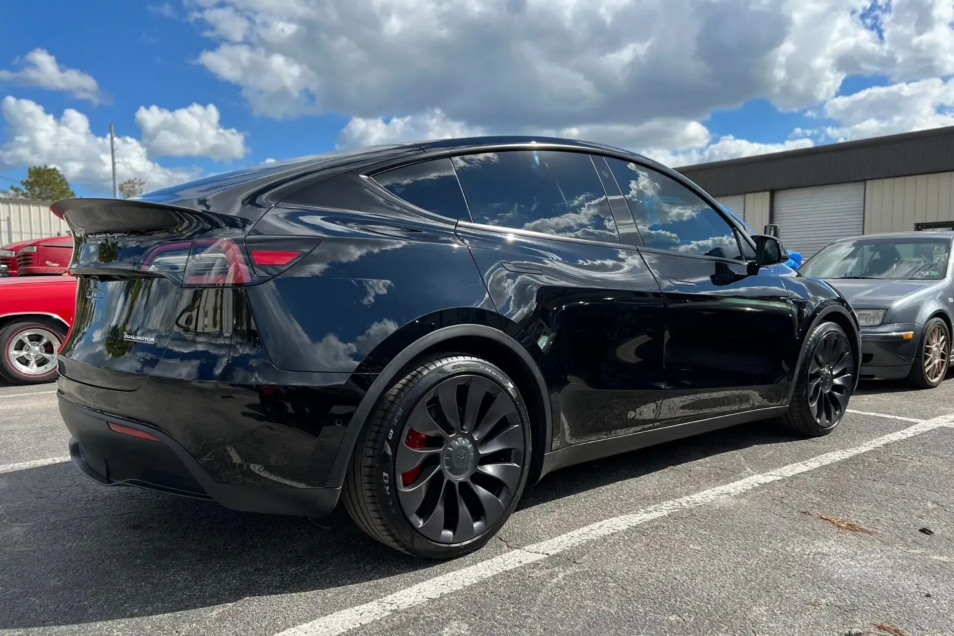 A black tesla model y is parked in a parking lot.